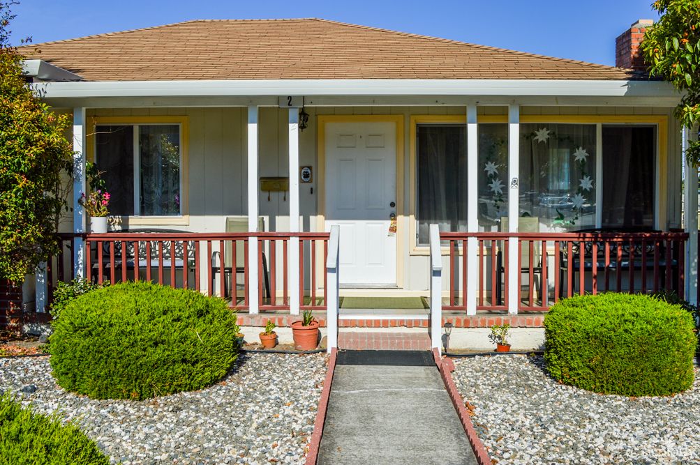 A small suburban house with a neatly manicured front yard and a welcoming front porch.