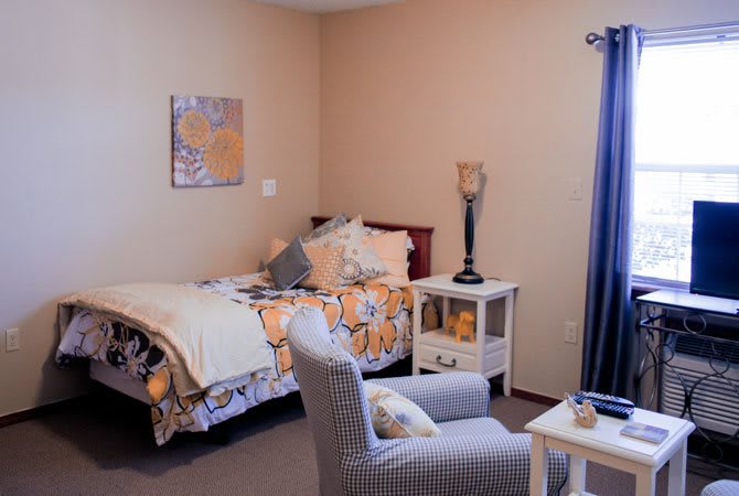 A cozy bedroom with a single bed, decorative pillows, and a comfortable chair.