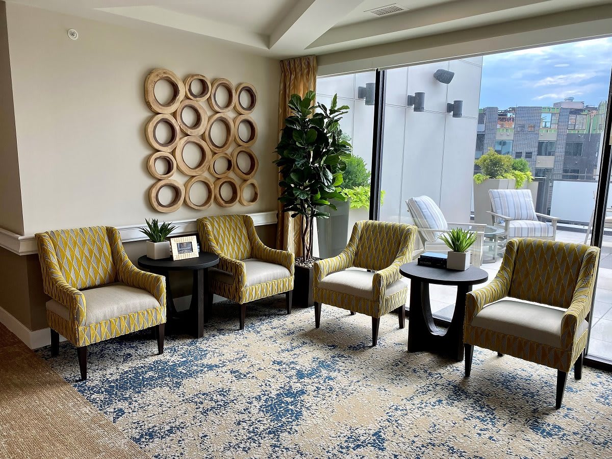 A cozy living room area with stylish chairs, decorative wall art, and a large window letting in natural light.