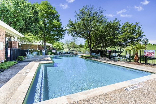 A serene outdoor swimming pool surrounded by lush trees and greenery.