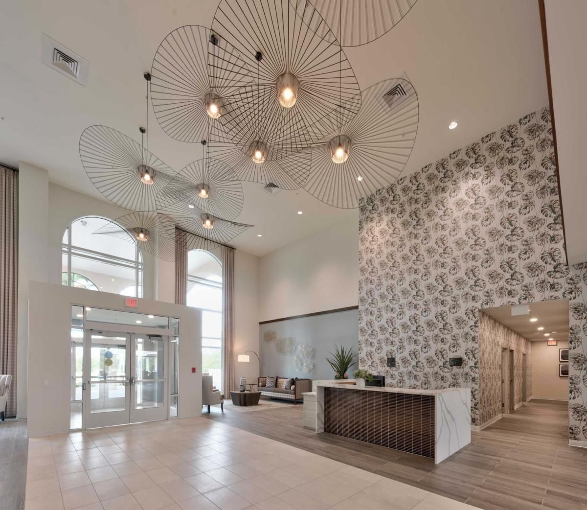 A modern lobby featuring a stylish chandelier and a decorated reception area.