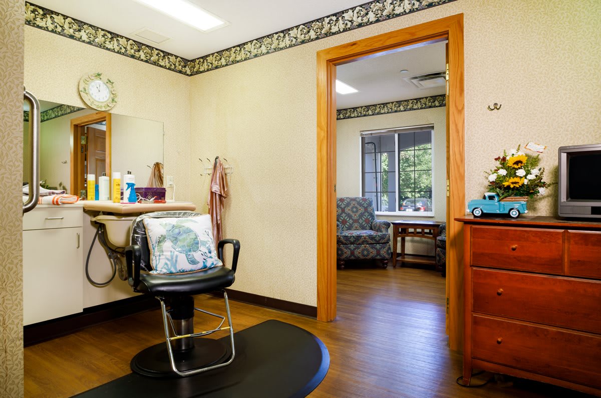 A cozy hair salon with a styling chair and mirror, featuring a comfortable waiting area.