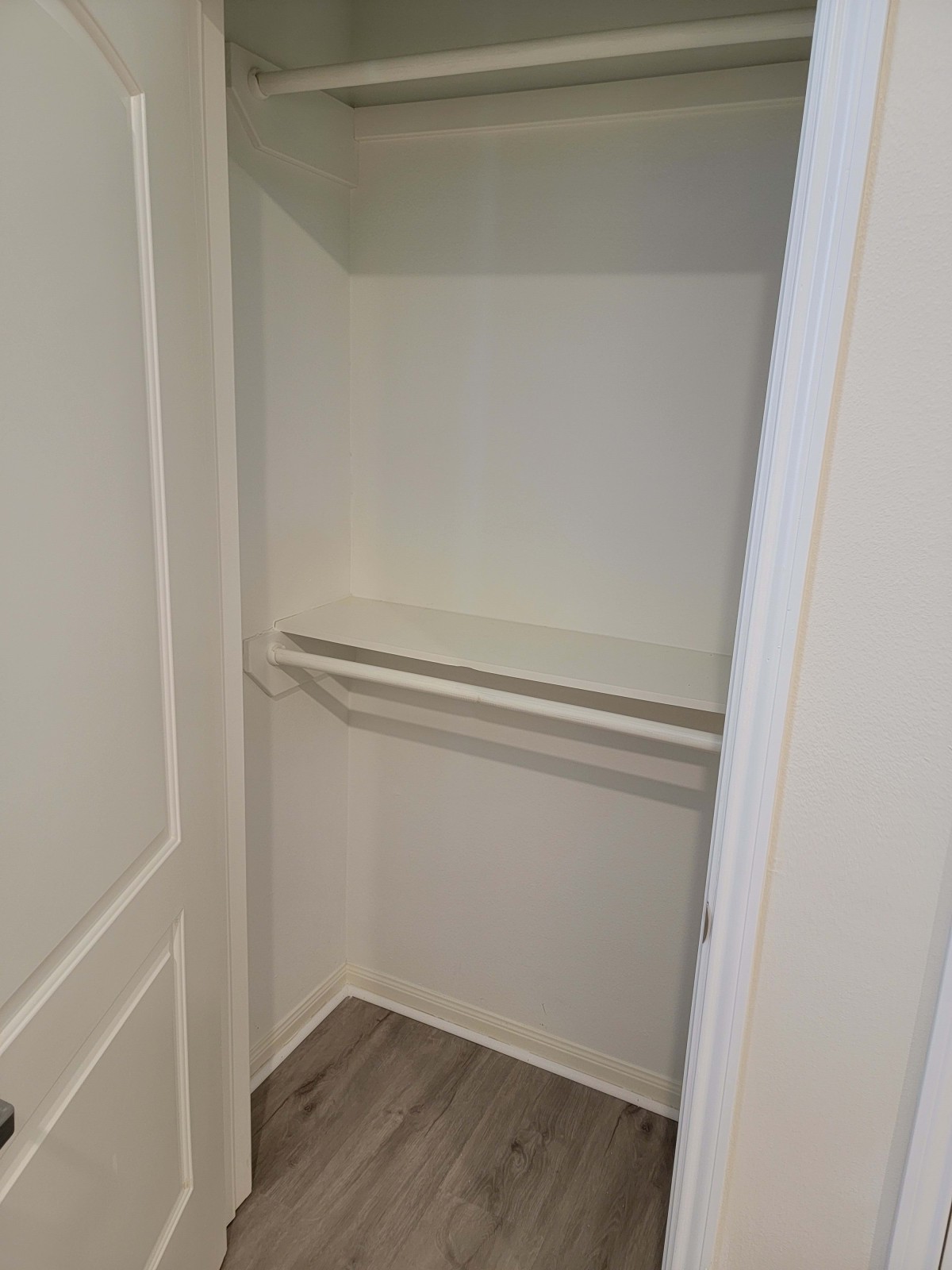 An empty closet with a hanging rod and shelf.