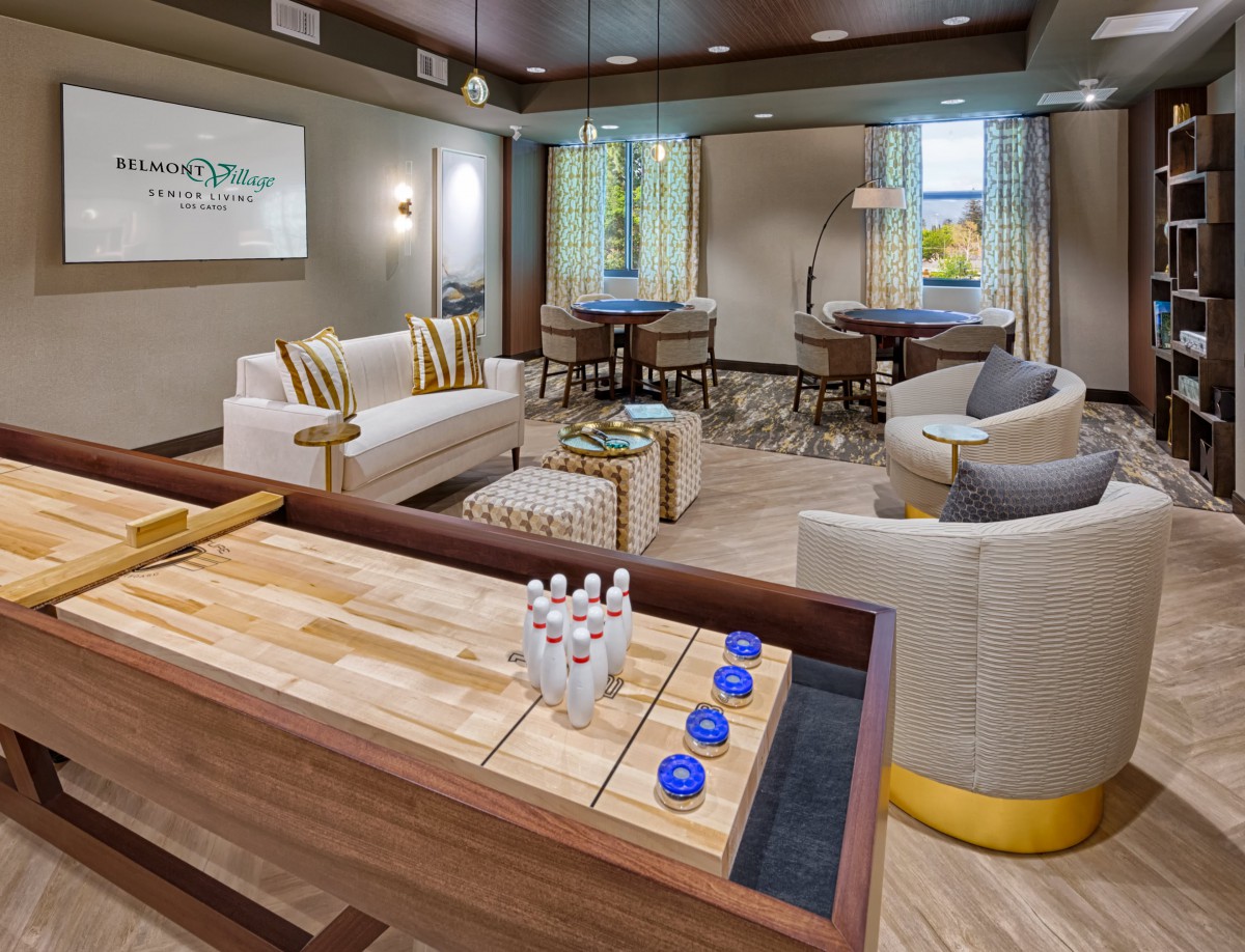 A modern living room with a shuffleboard table and comfortable seating.