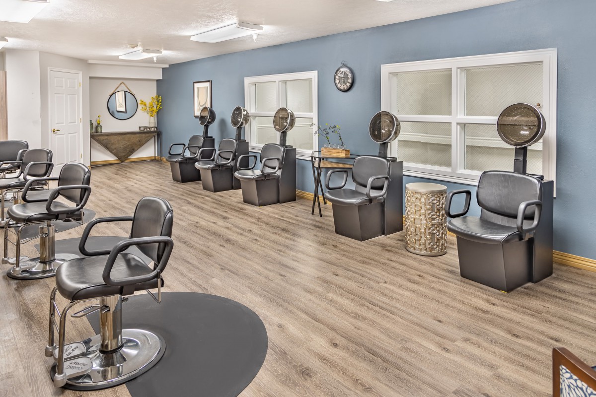 Interior view of a modern hair salon with styling chairs and hair dryers.