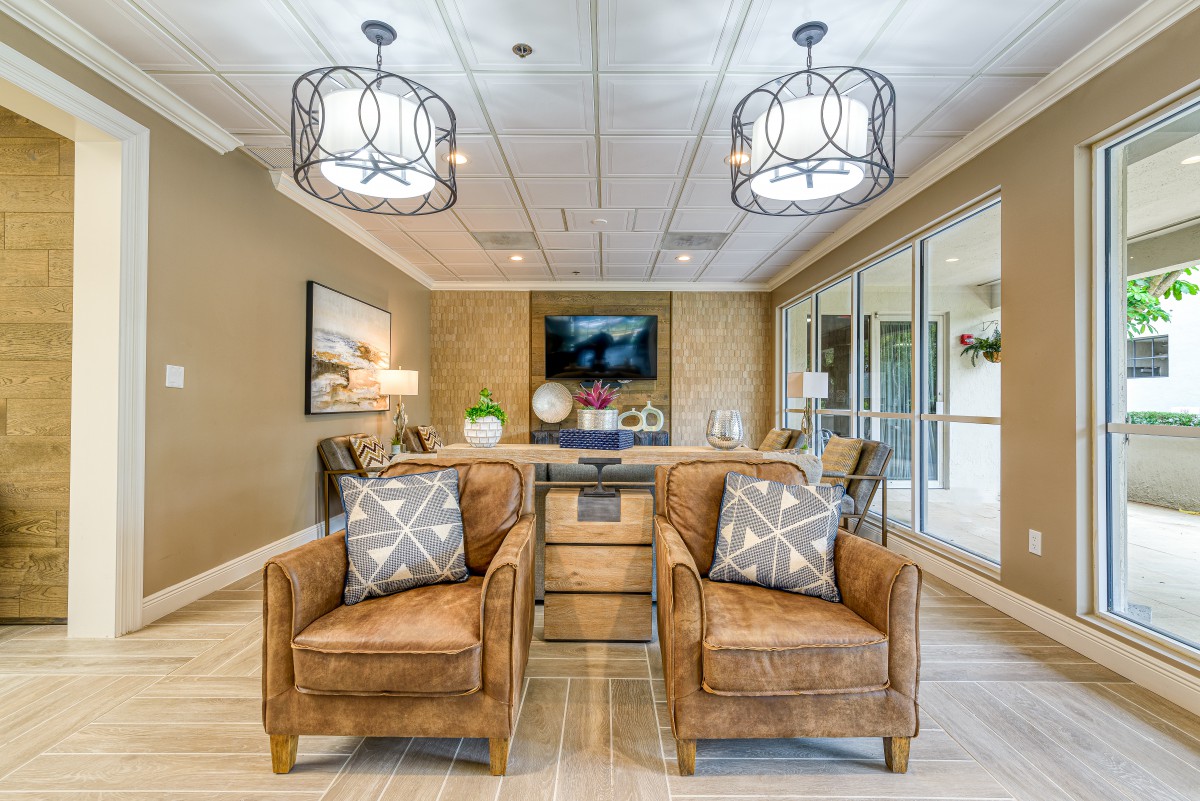 A modern lounge area with comfortable leather chairs, stylish lighting fixtures, and a TV mounted on the wall.