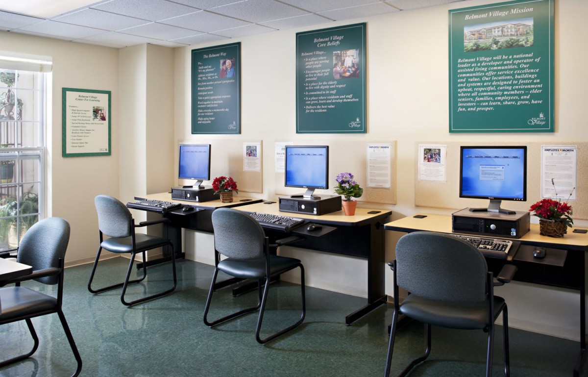 A neat computer lab with several workstations and chairs arranged in a row.