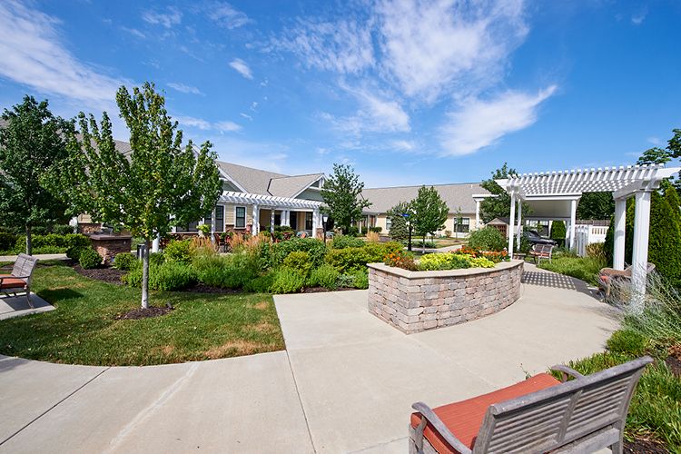 A scenic view of a landscaped garden area with a pathway leading to a residential building under a blue sky.