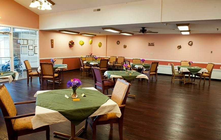 A cozy dining area with neatly arranged tables and chairs, decorated in warm tones.