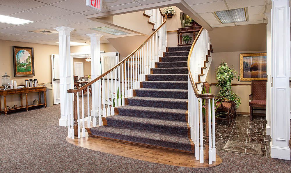 An elegant indoor staircase with a carpeted path and wooden handrails, leading to an upper floor in a well-decorated space.