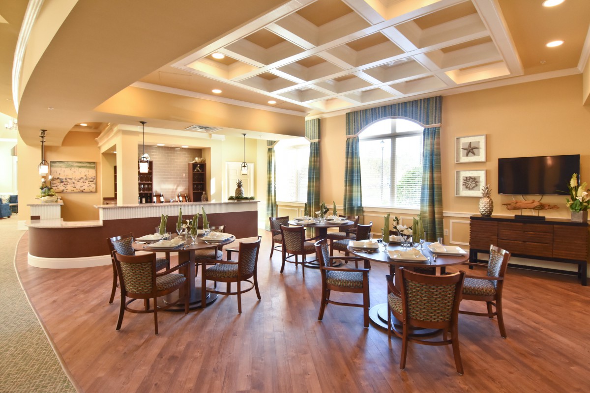 A stylishly designed restaurant dining area with tables and chairs, featuring natural lighting and wood flooring.