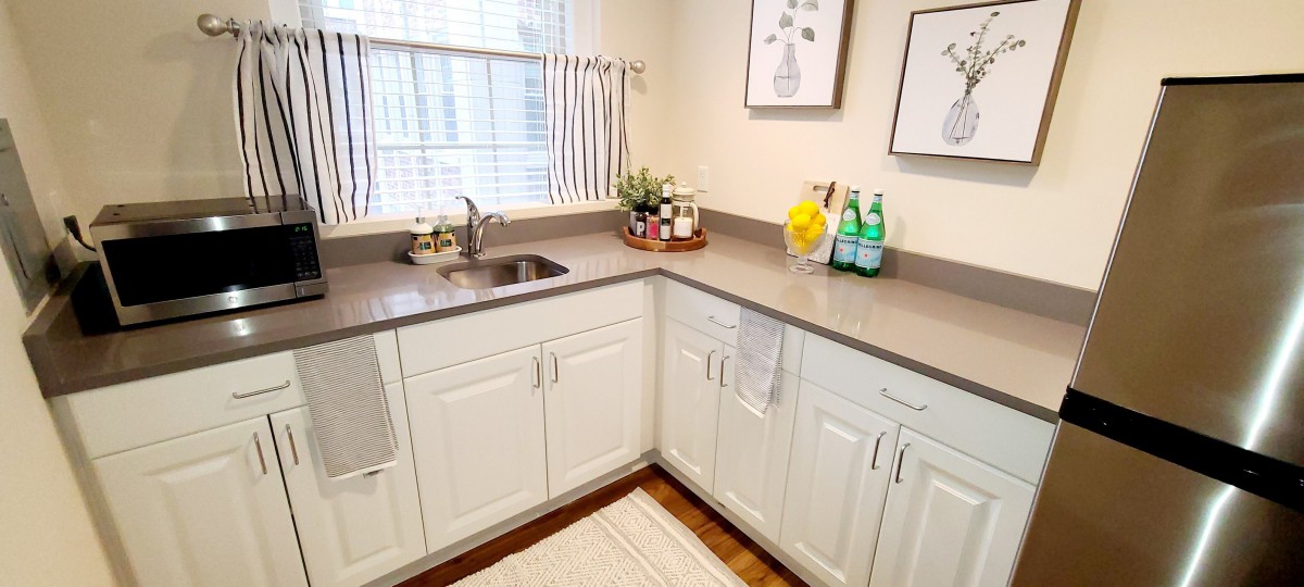 A clean, modern kitchen with white cabinets and a gray countertop.