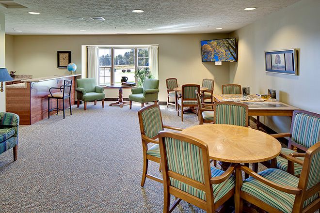 A spacious meeting room with tables and chairs, featuring large windows and artwork on the walls.