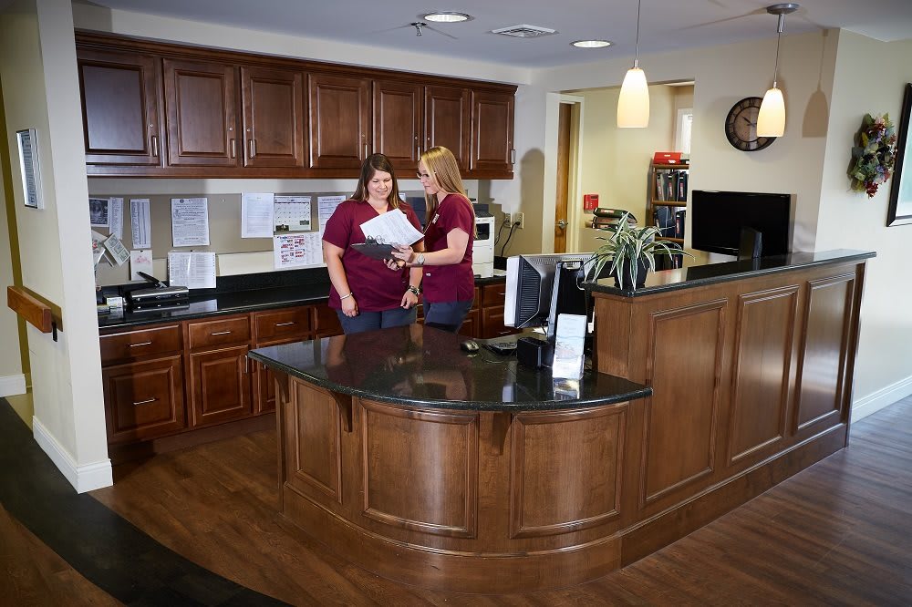 Two people working at a reception desk in an office setting.