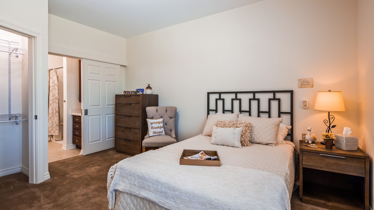 A cozy bedroom with a neatly made bed, dresser, and comfortable chair.