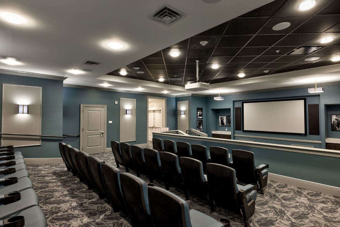 A modern home theater with rows of comfortable seating and a large projection screen.
