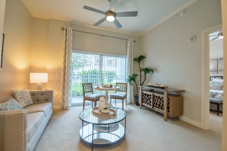 A cozy living room with a dining area, featuring a ceiling fan, coffee table, and stylish decor.