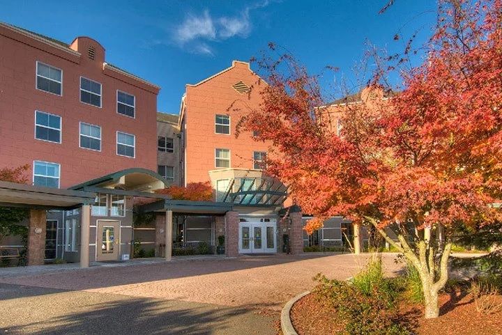 A brick building entrance surrounded by vibrant autumn foliage under a clear blue sky.