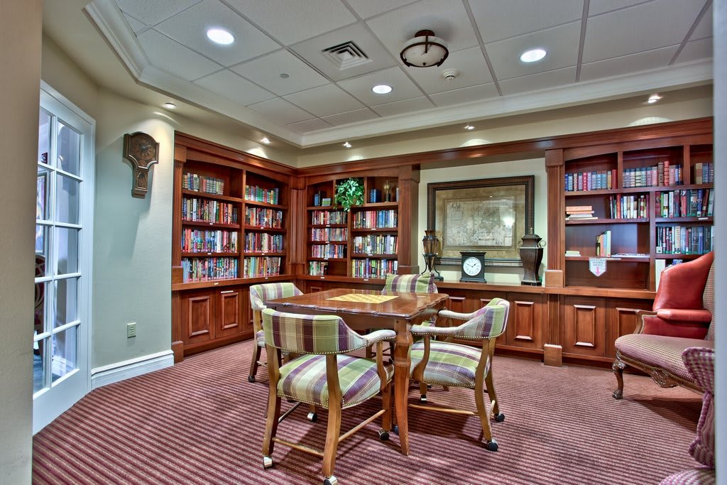 A cozy library space with wooden bookshelves and a round table surrounded by chairs.