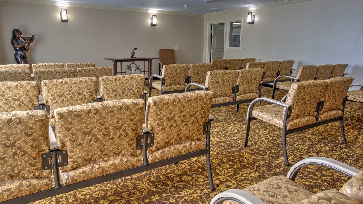 An empty conference room with rows of chairs and a microphone setup at the front.