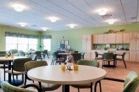 A cozy dining area with tables and chairs, adjacent to a kitchen space.
