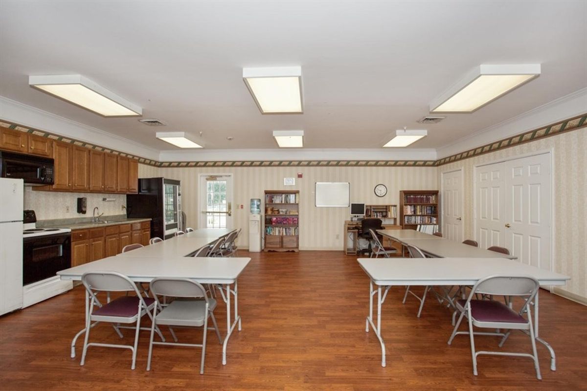 A multipurpose room with tables, chairs, and a kitchen area.