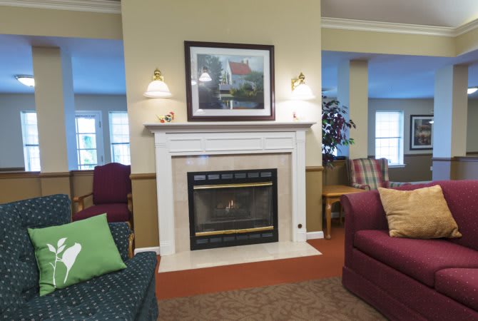 A cozy living room featuring a central fireplace surrounded by comfortable seating and artwork on the wall.