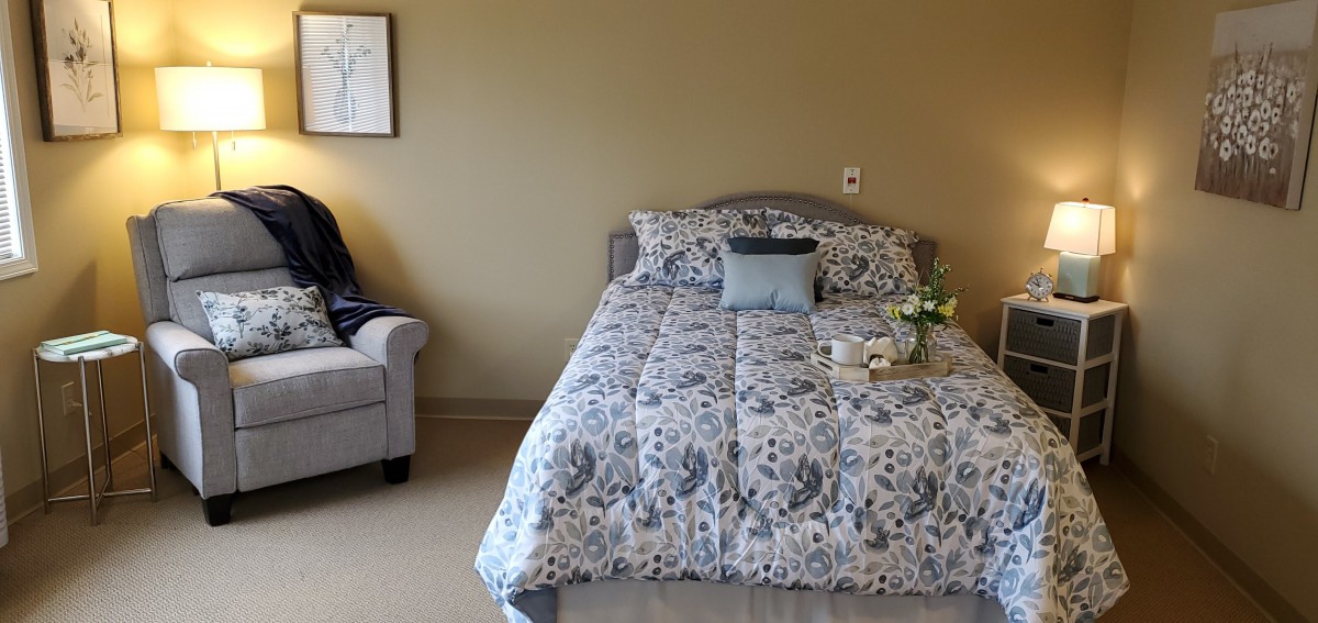 A cozy bedroom with a patterned comforter and a small side table with a lamp.