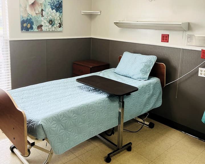A clean and organized hospital room with a bed and side table.