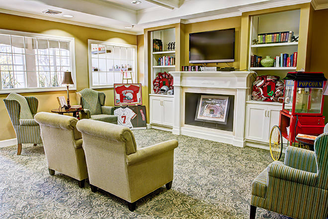 A cozy living room with comfortable seating, a fireplace, and a TV mounted above built-in bookshelves.