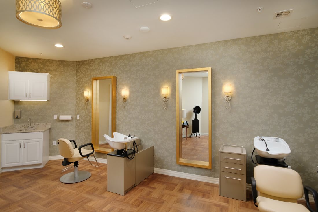 A modern salon interior featuring hair styling chairs, large mirrors, and elegant lighting fixtures.