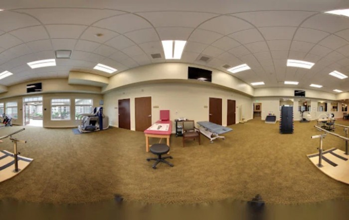 A spacious therapy room with exercise equipment and medical beds, designed for rehabilitation purposes.