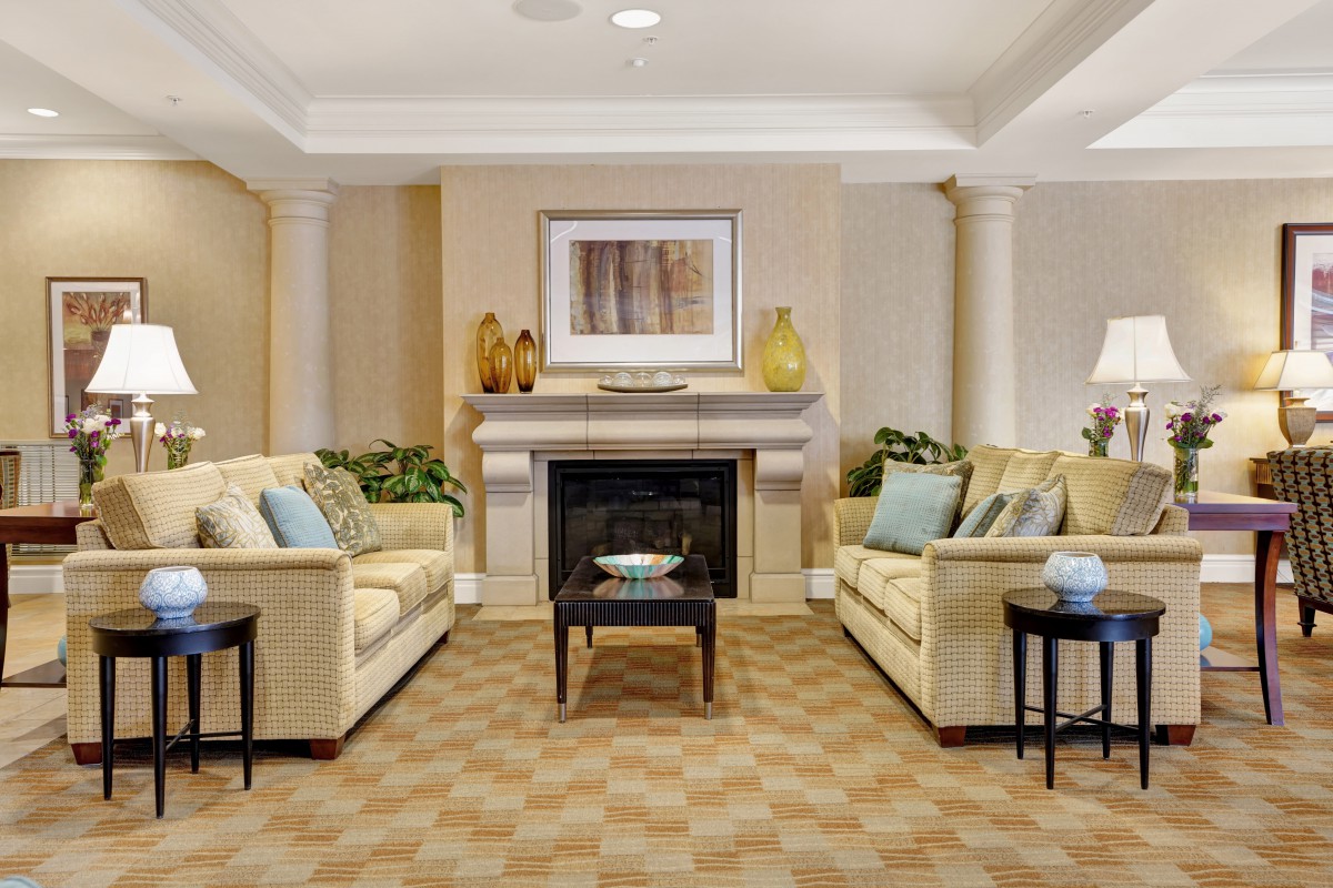 Cozy living room with beige sofas and a central fireplace.