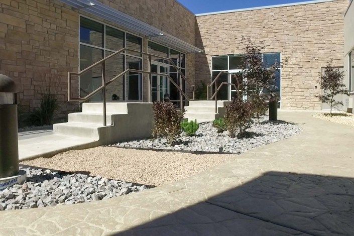 A modern building exterior with steps and landscaped areas featuring rocks and plants.