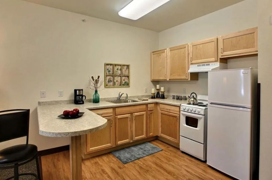A modern kitchen with wooden cabinets and appliances in an apartment setting.