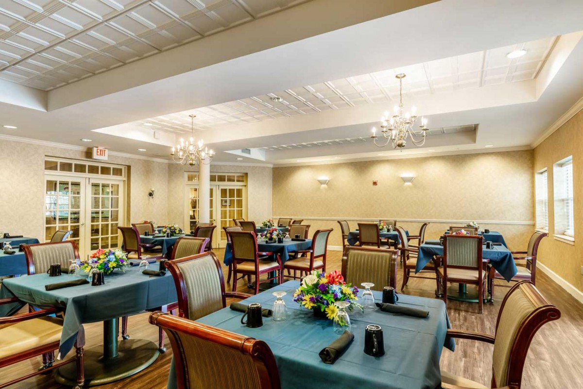 Elegant dining room with neatly arranged tables and chandeliers.