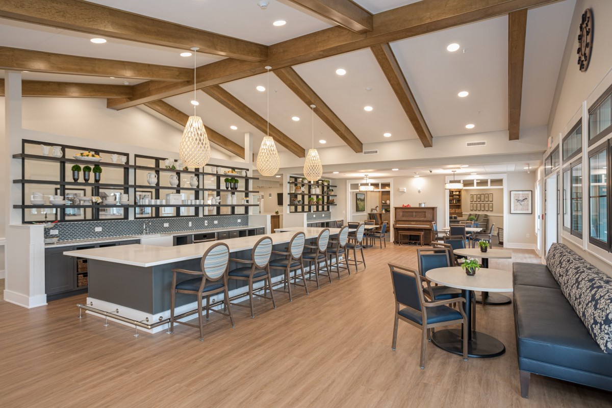 A modern interior featuring a bar and dining area with elegant wooden beams and pendant lighting.