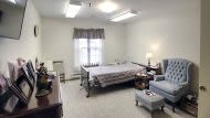 A neatly organized healthcare facility room with a single hospital bed and furniture.