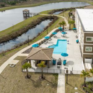 Aerial view of a modern building with an outdoor pool adjacent to a canal.