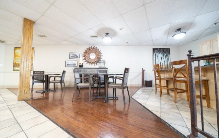 A modern dining area with tables and chairs arranged on a wooden floor.
