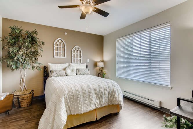 A cozy and well-lit bedroom with a comfortable bed, warm decor, and a large window.