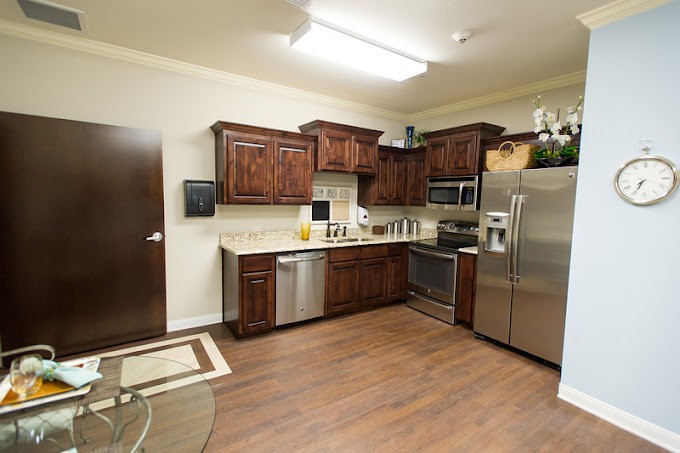 A modern kitchen with wooden cabinets, stainless steel appliances, and hardwood flooring.