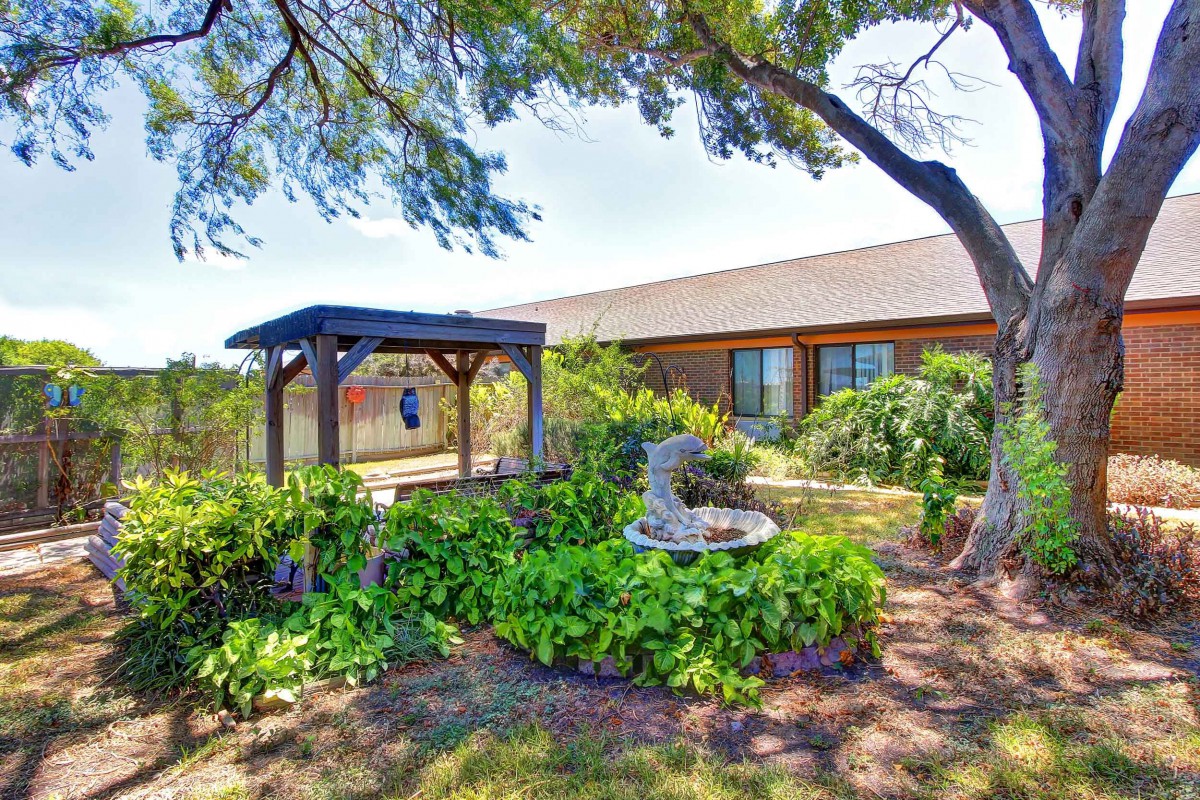 A tranquil garden scene with lush greenery and a charming building in the background.