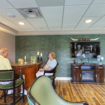 Two people seated at a bar in a warmly decorated interior space.
