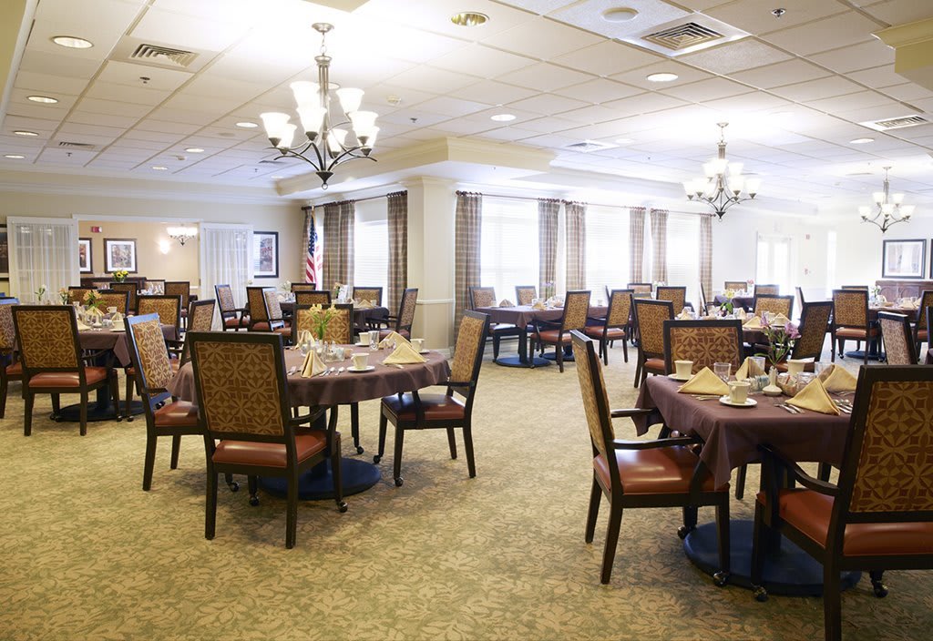Spacious dining area with neatly arranged tables and elegant chandeliers.