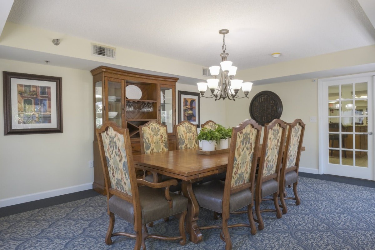 A spacious dining room featuring a large wooden dining table, ornate chairs, and a chandelier.