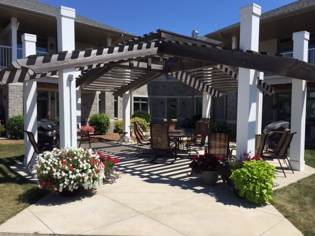 A sunny outdoor patio with a pergola and garden seating area.