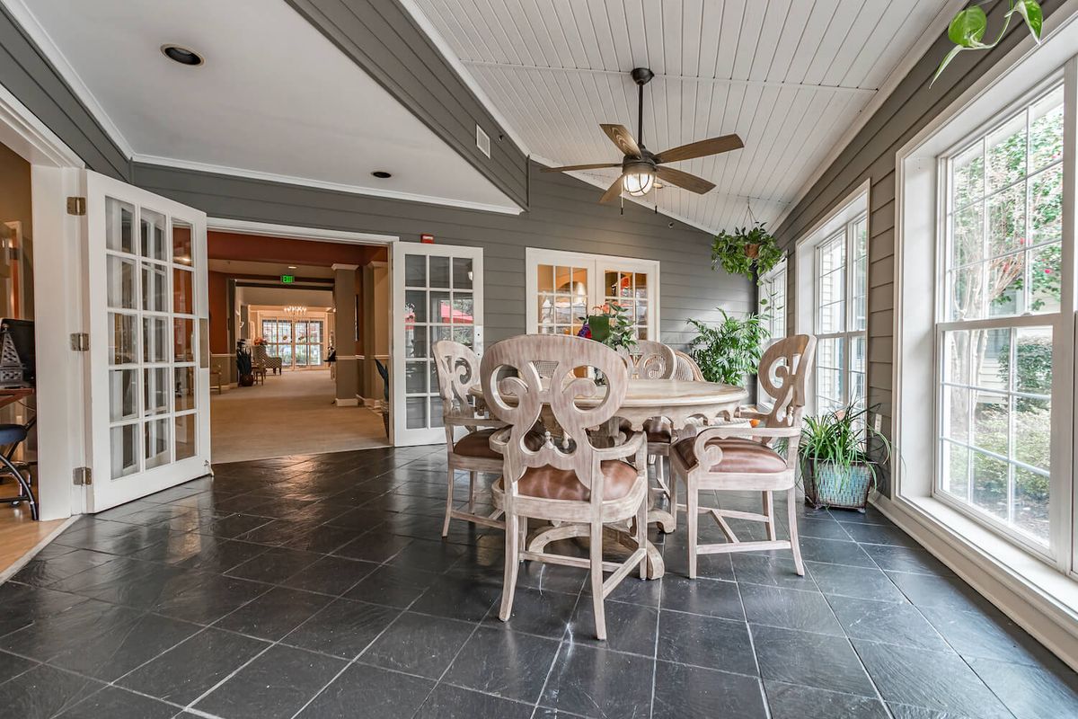 A stylish dining area featuring elegant furniture, a ceiling fan, and large windows for natural light.