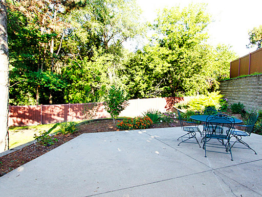 A serene outdoor patio surrounded by lush green trees and a cozy seating area.