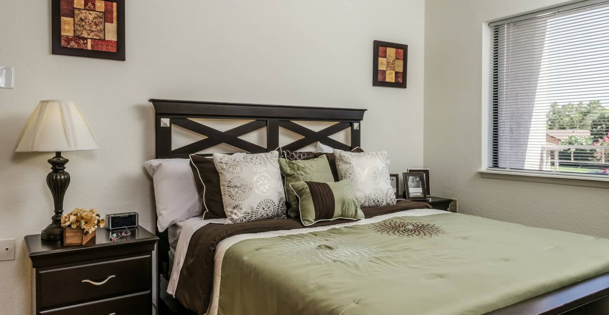 A well-decorated bedroom featuring a comfortable bed with multiple pillows and a stylish headboard.